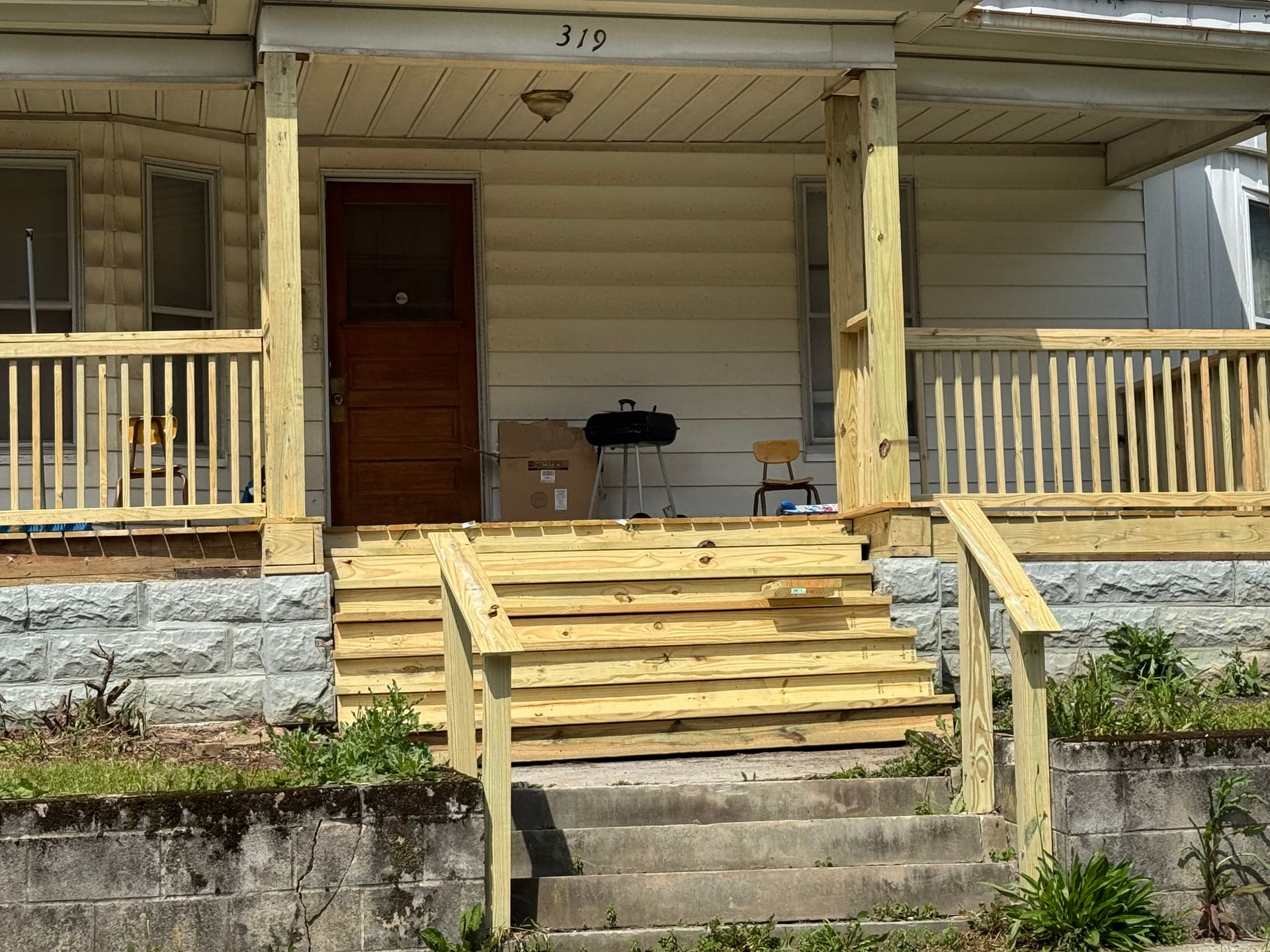 Newly rebuilt pressure-treated front porch with new steps, railings, and posts