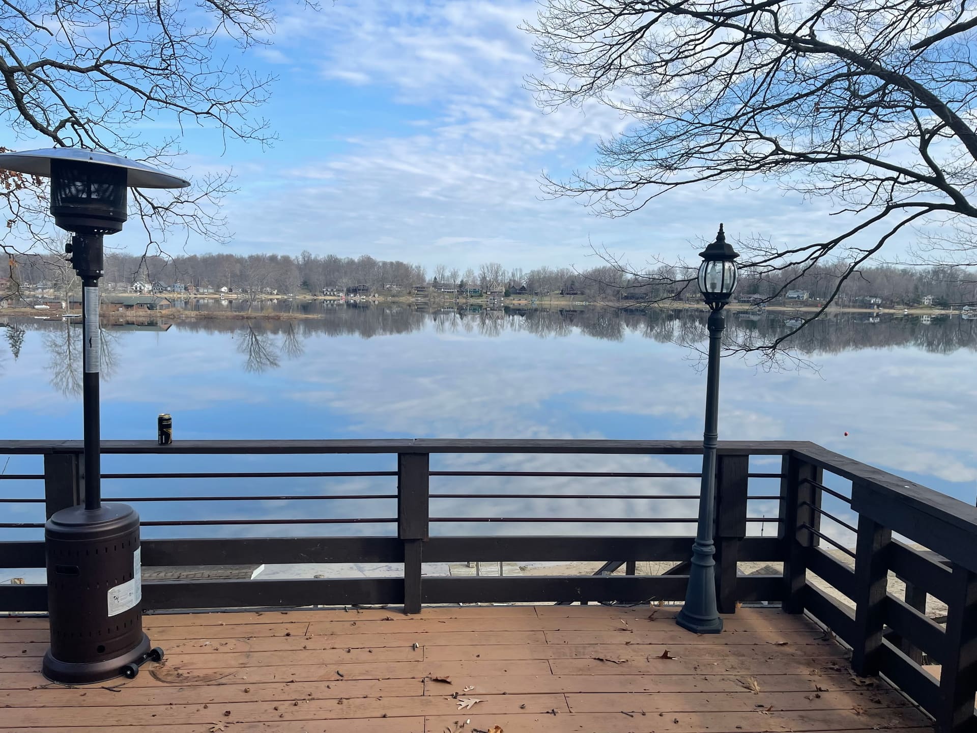 Wood deck with railing overlooking a calm lake on a clear winter morning