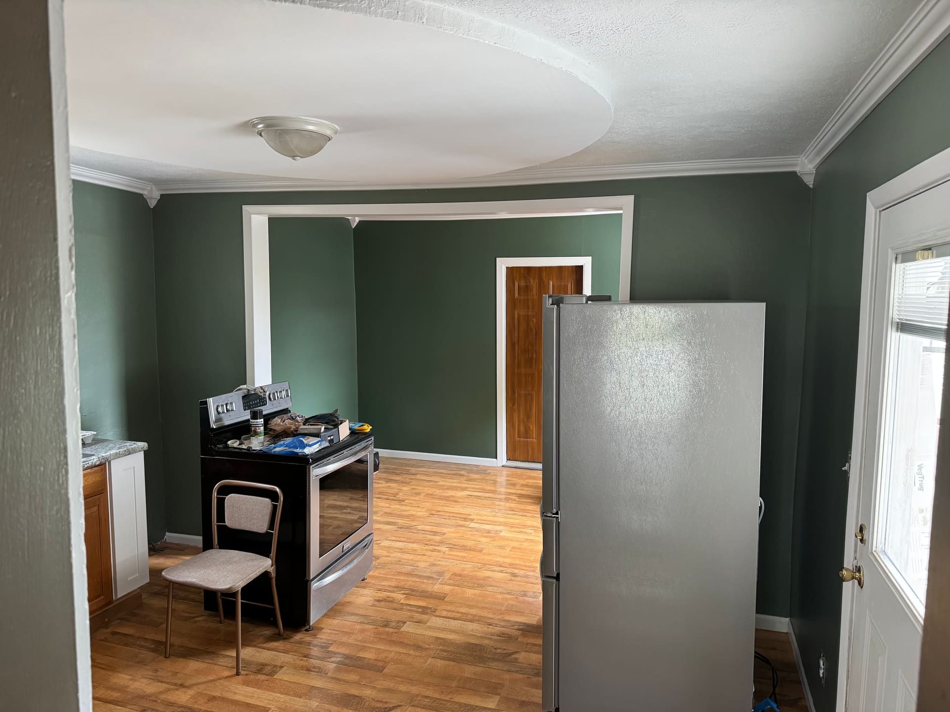 Kitchen interior painted in sage green with crisp white ceiling and trim