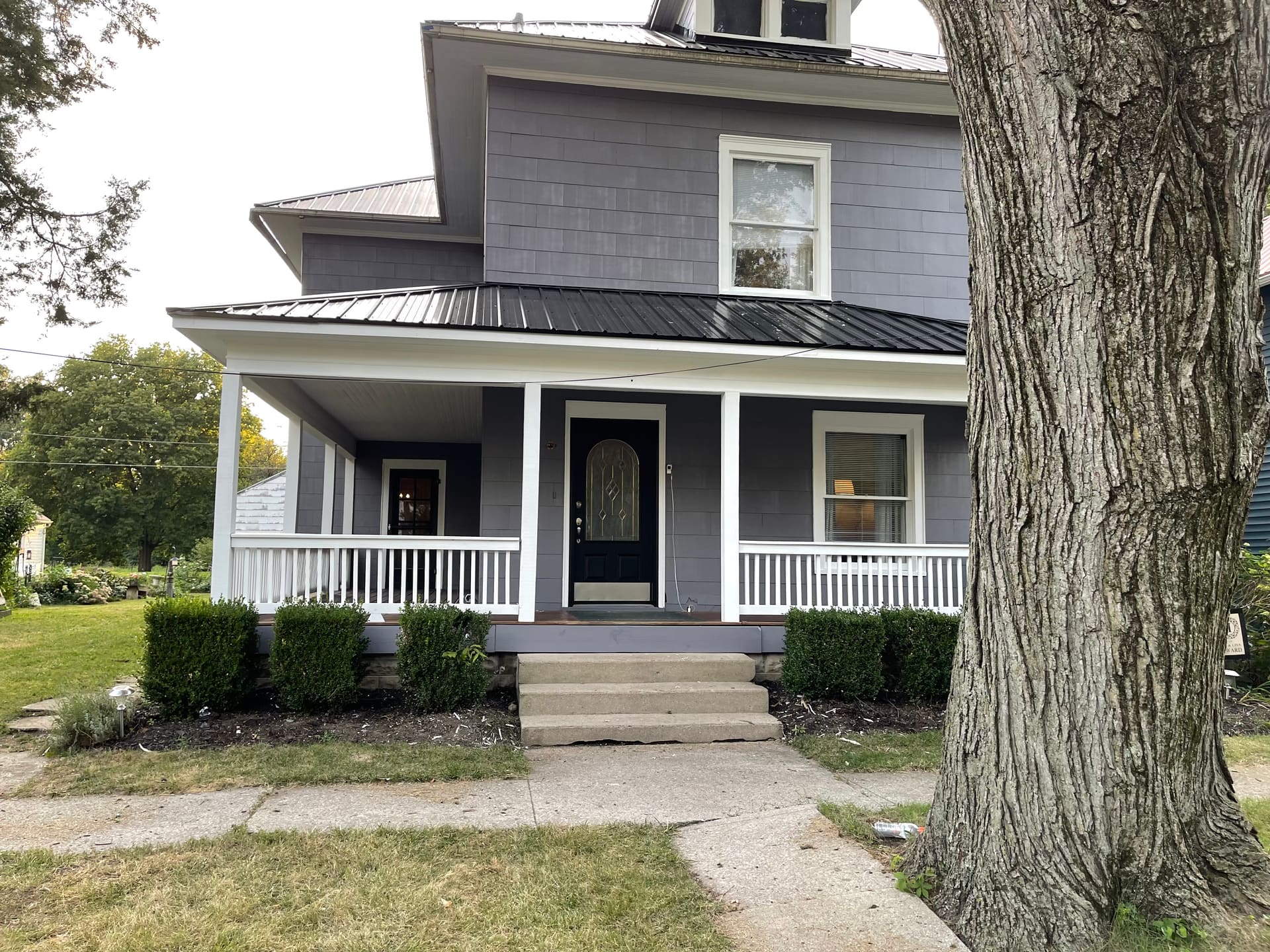 Two-story Victorian home with freshly painted gray siding, white trim, and rebuilt front porch